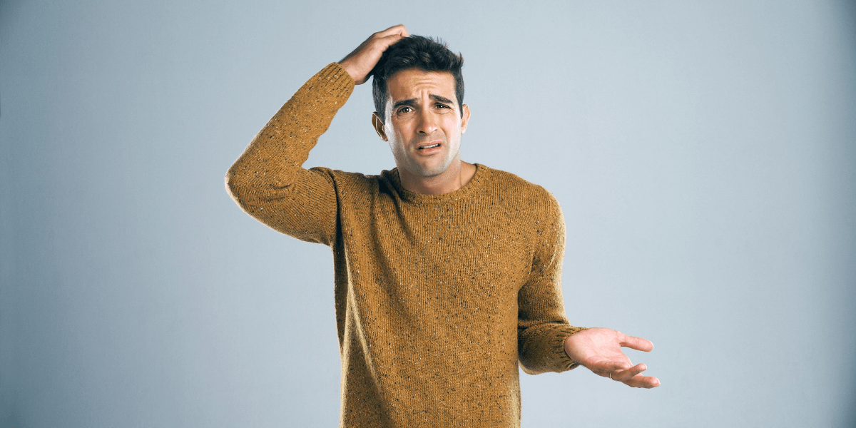 A confused man scratches his head and shrugs.