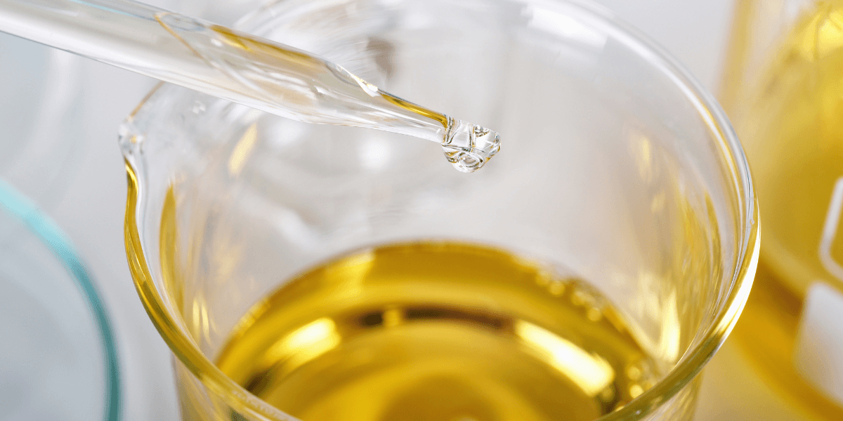Close-up of a dropper adding liquid to a glass beaker